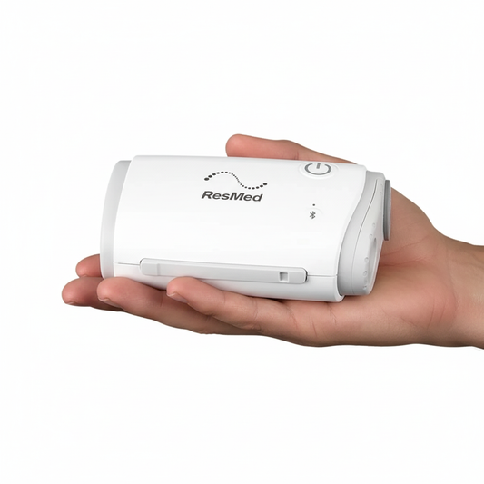Hand holding a ResMed device against a white background